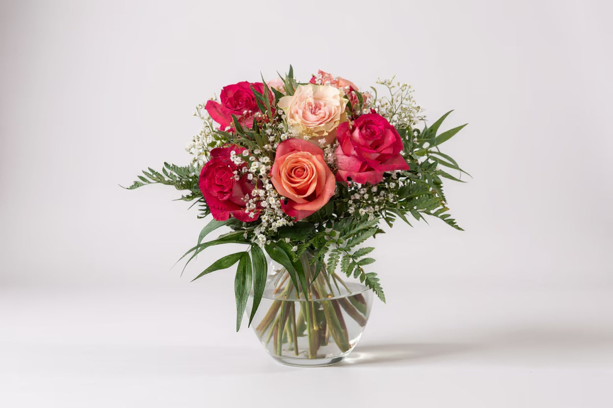 Blumenstrauß in Rosa Tönen in grüner Vase vor hellem Hintergrund